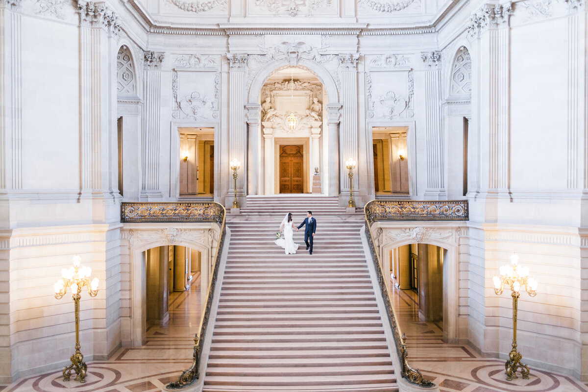 Bride and Groom walking down San Francisco City Hall grand staircase