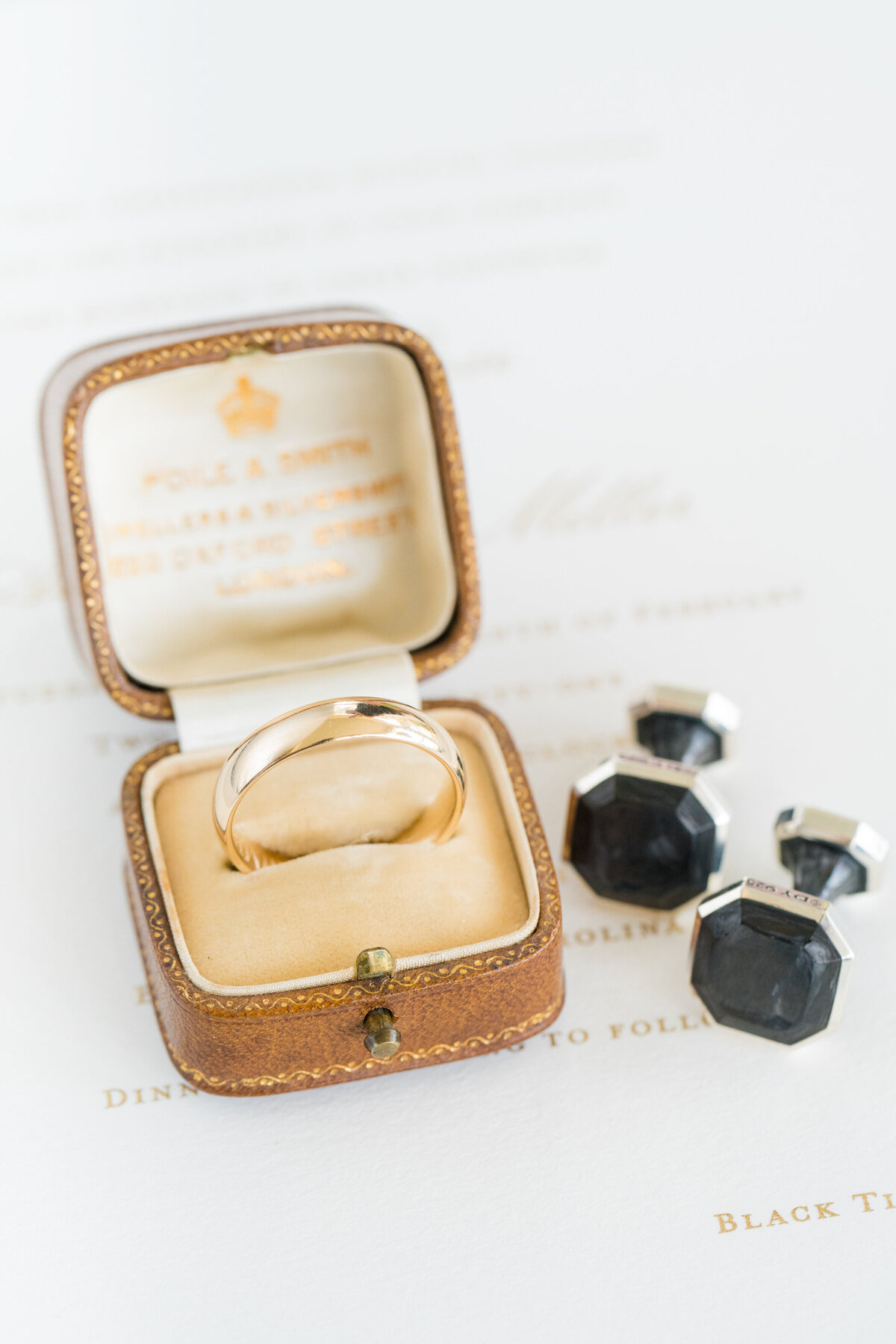 groom's gold wedding band and cufflinks styled on invitation
