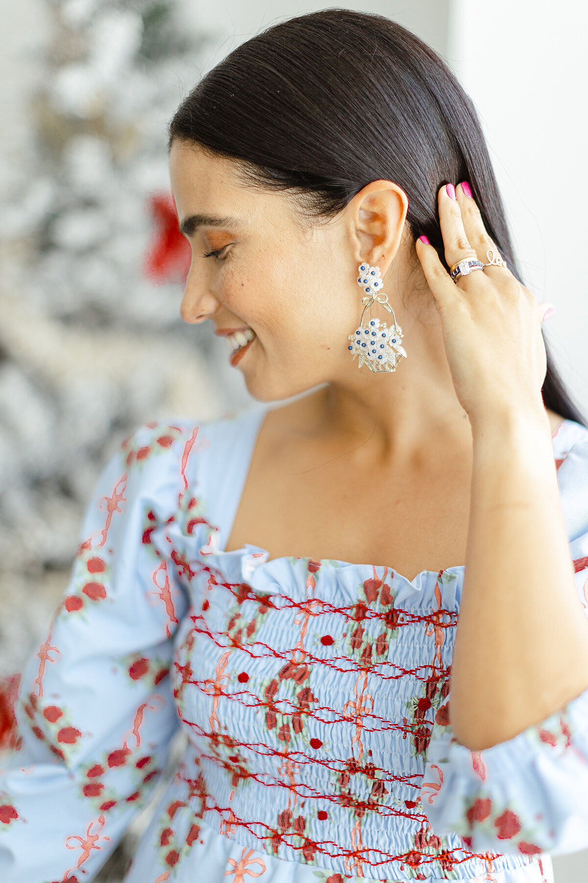 A model wearing a Dondolor christmas dress posing as she is holding her hair back to show off her holiday earrings.