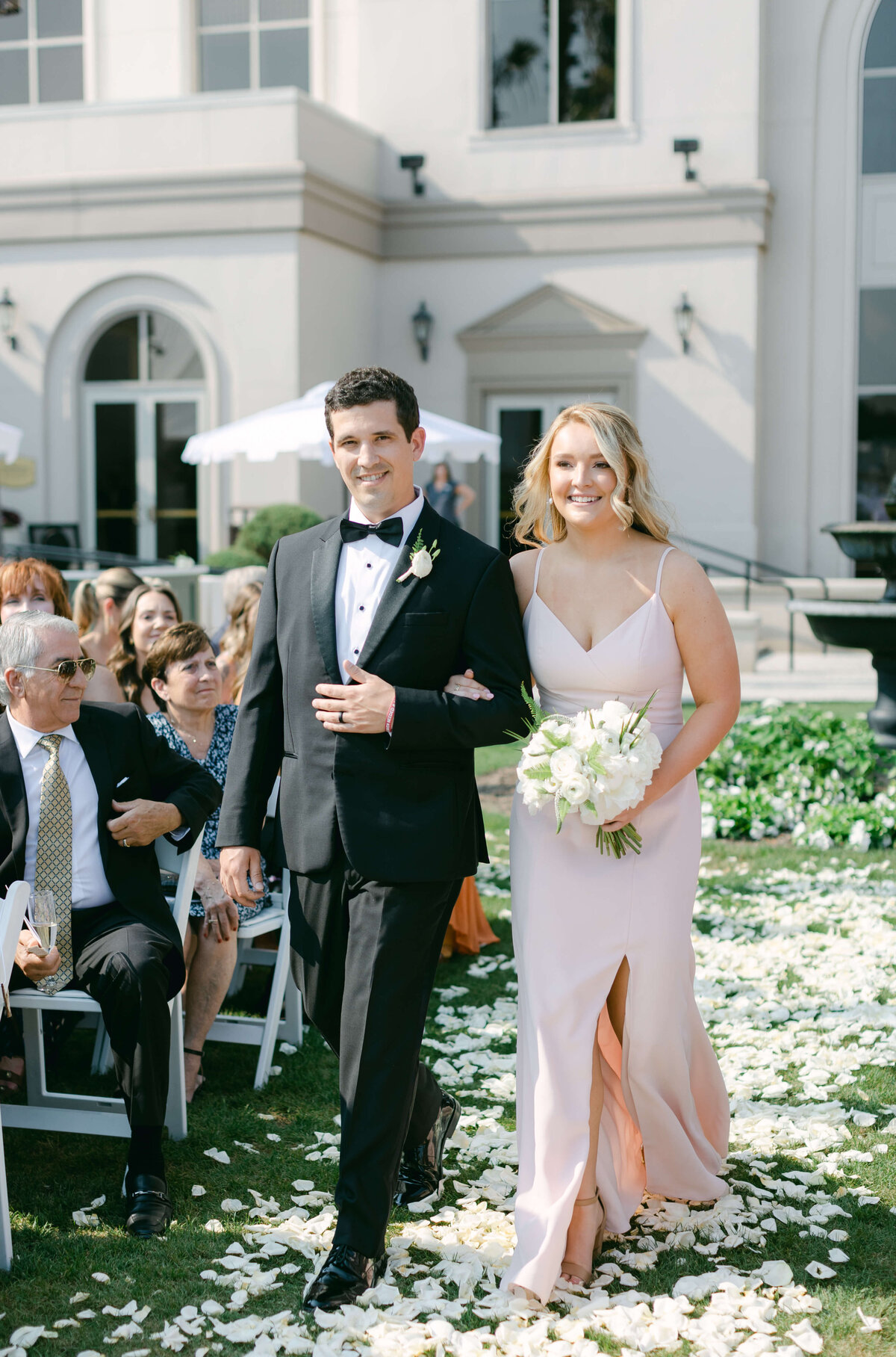 A bridesmaid and groomsmen walk down the aisle.