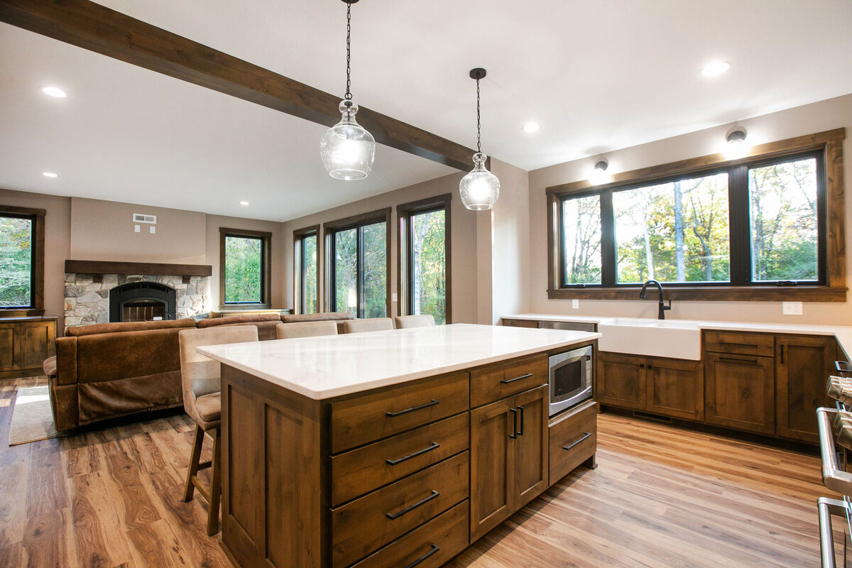 Open kitchen with dark cabinets, large island, and quartz countertops in an Big Lake Township custom home
