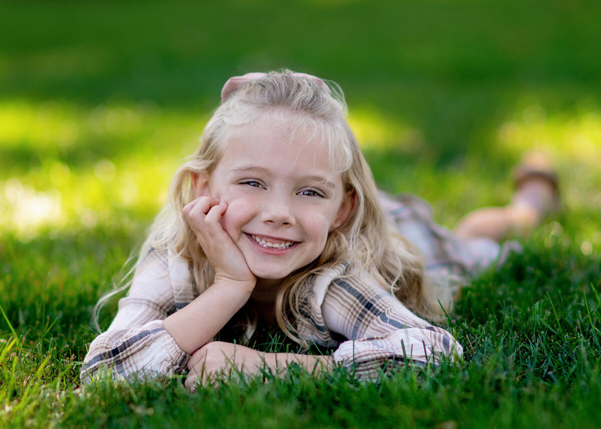 Girls lays in grass in a park while smiling