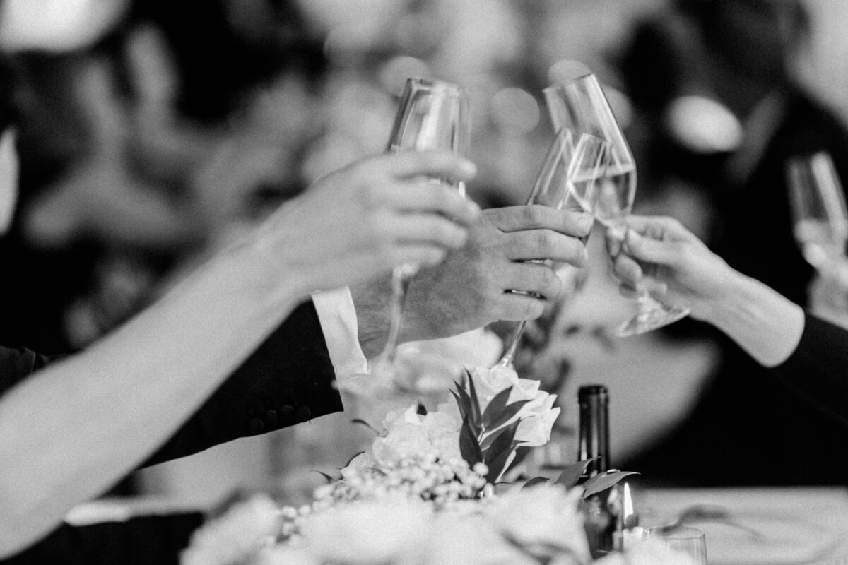People cheering for bride and groom. hand in the frame with wine glasses