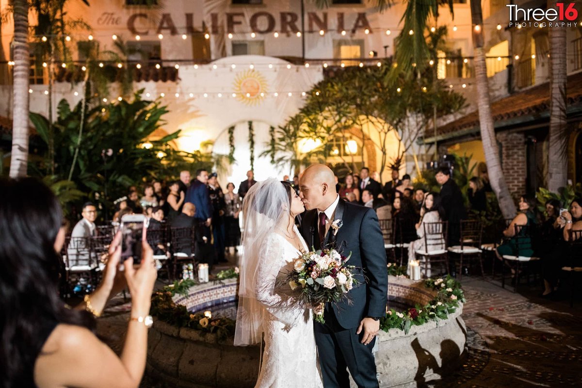 Newly married couple stops for a kiss walking down the aisle