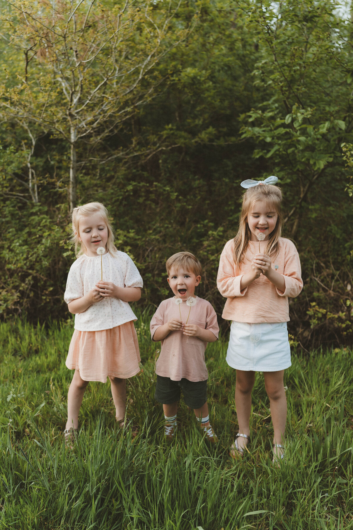 Drie kinderen blazen blaasbloemen.