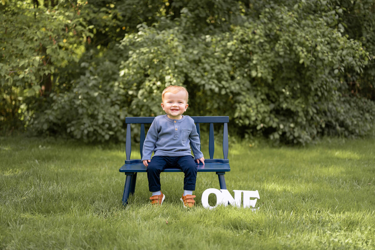 boy sitting on a bench with a "one" sign