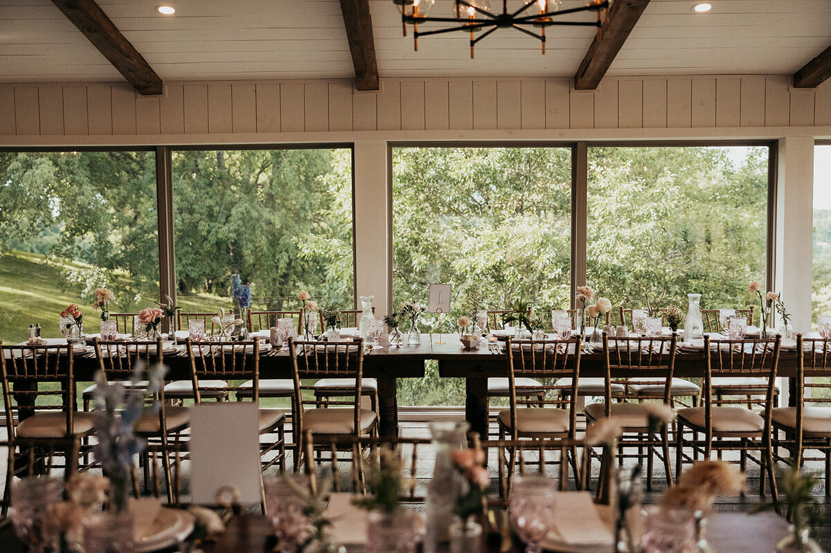 color image of Willowbrook wedding venue with farmer's tables set for the reception with colored glassware and fresh flowers