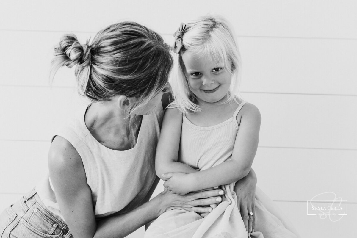 Mom snuggles daughter who is camera shy