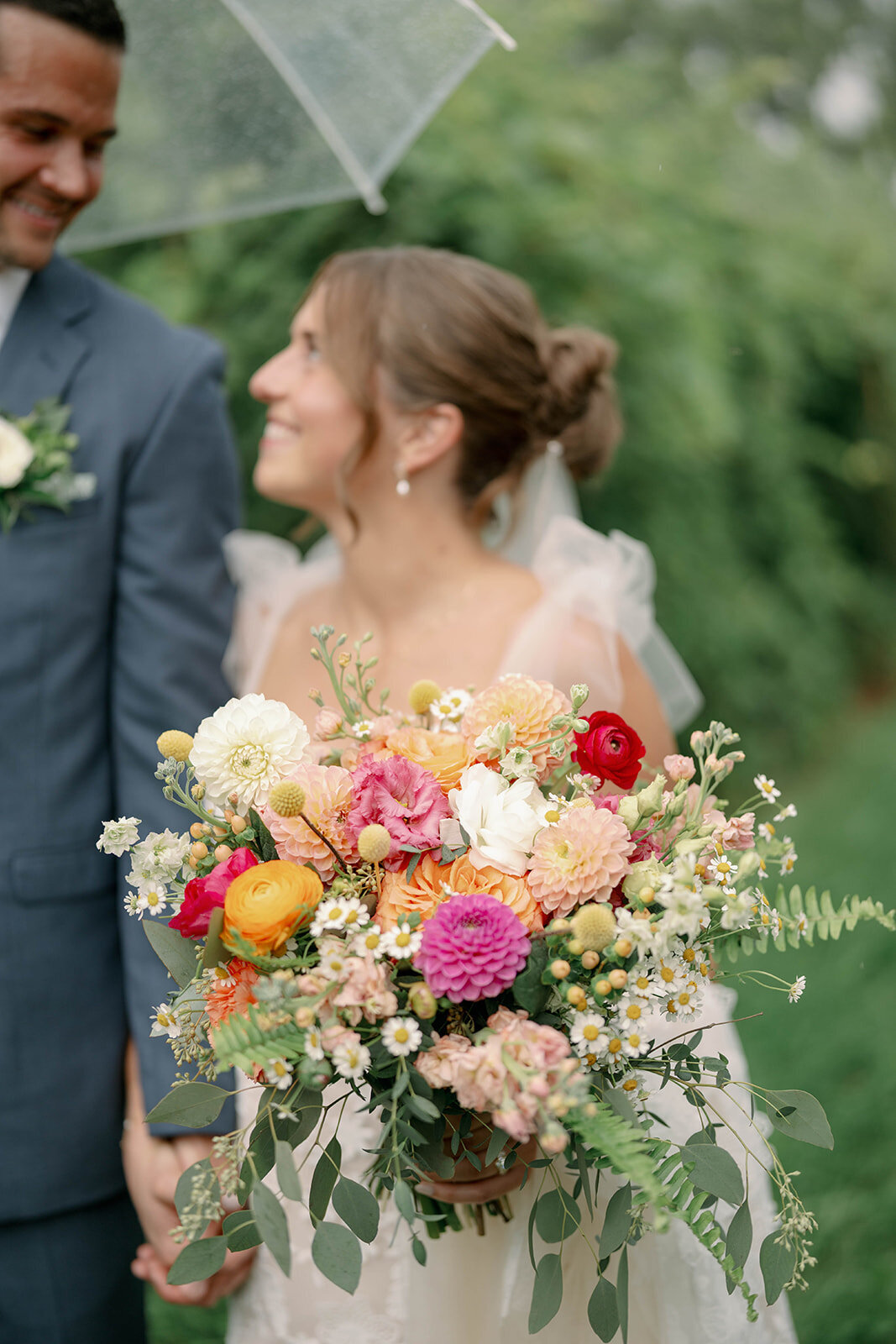 Romantic portrait of the bride smiling up at her groom while holding her colorful fall bouquet during their Cherry Barn wedding in Frankfort, Michigan.