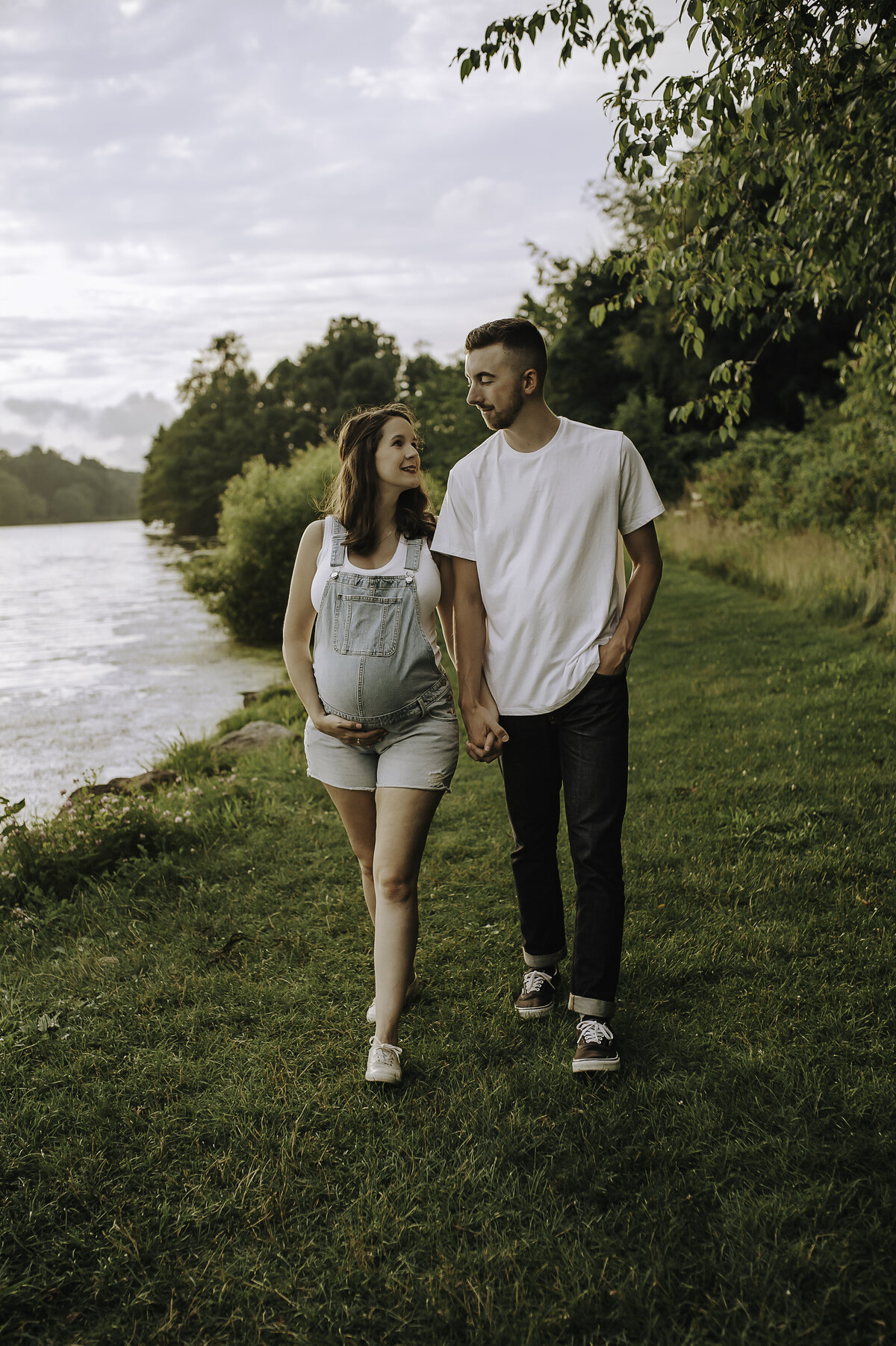 Verona B Photography captures a beautiful maternity picture of an expectant mom and her husband holding hands, walking, and gazing at each other at Silver Creek metro Park in Norton, OH. The couple’s love for each other and joy in anticipation of their baby was evident on their faces in this beautiful lake setting near Akron, OH.
