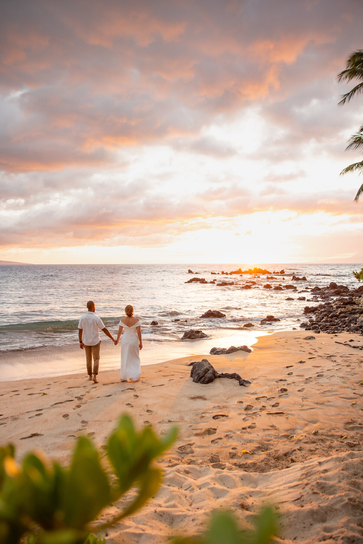 Maui Wedding Photographer captures bride and groom holding hands while walking on beach