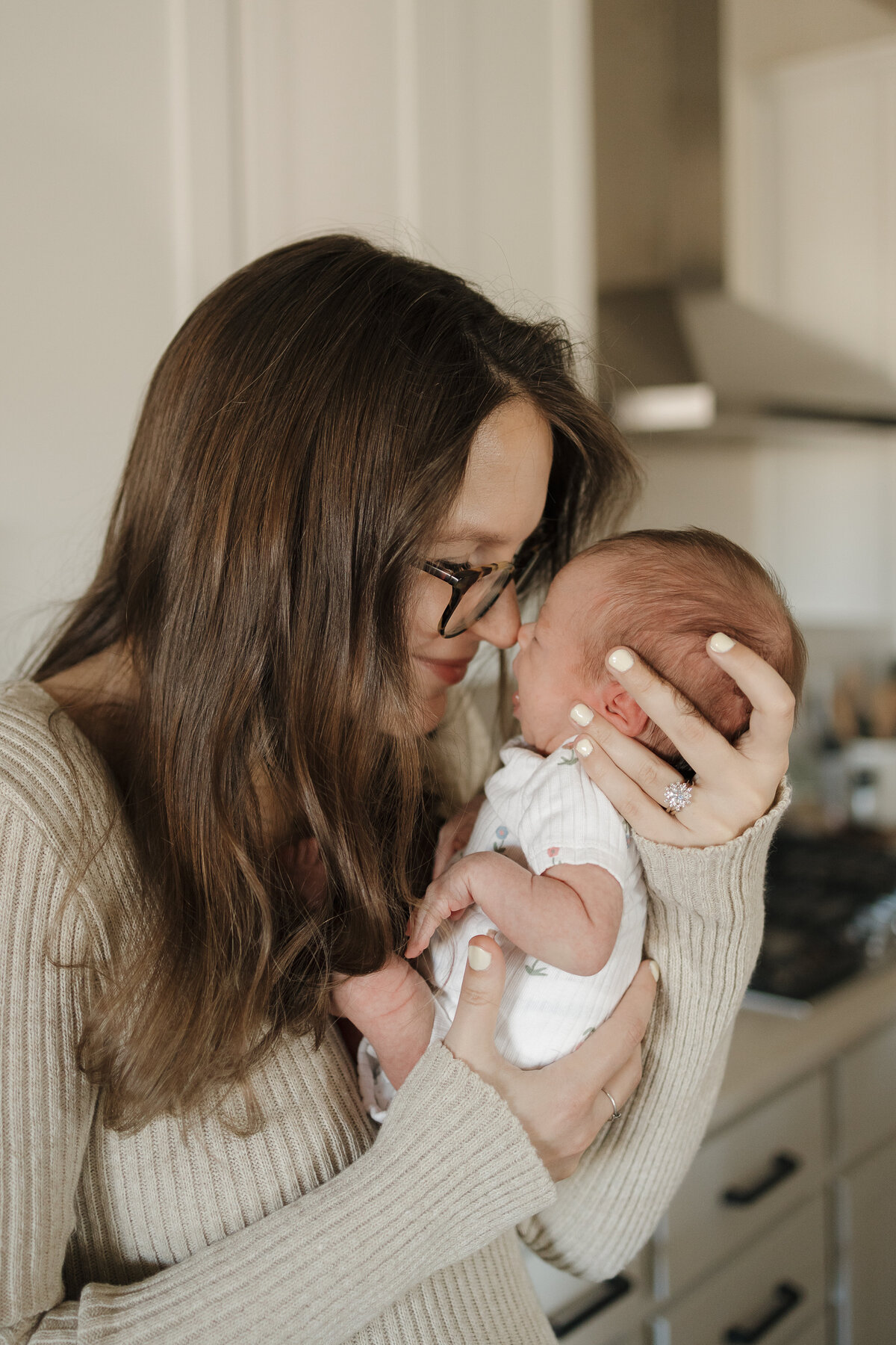 Longmont mom and newborn touching noses standing in kitchen during in home newborn session with alexis adkins photography