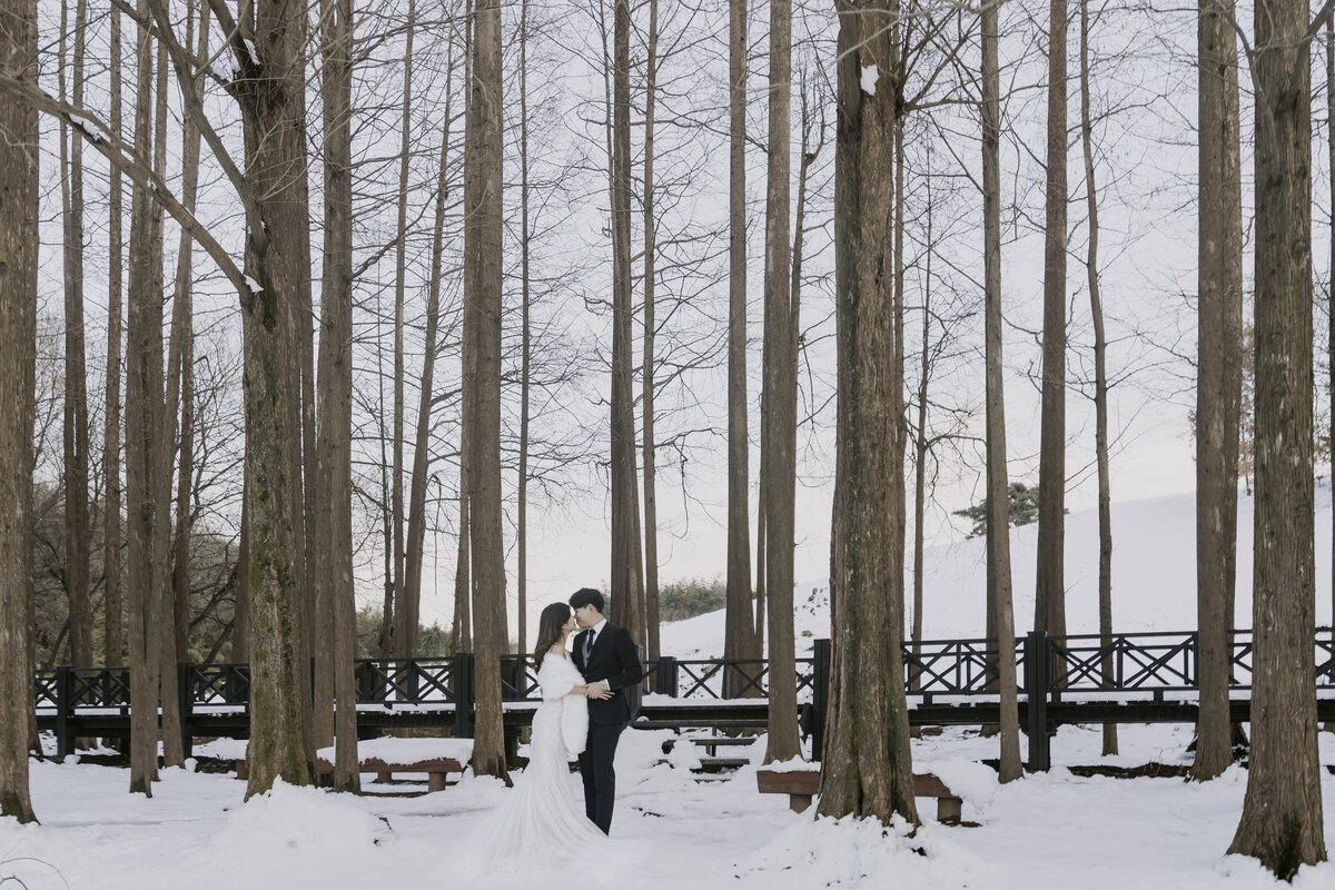 the couple lean for a kiss in snowy forest