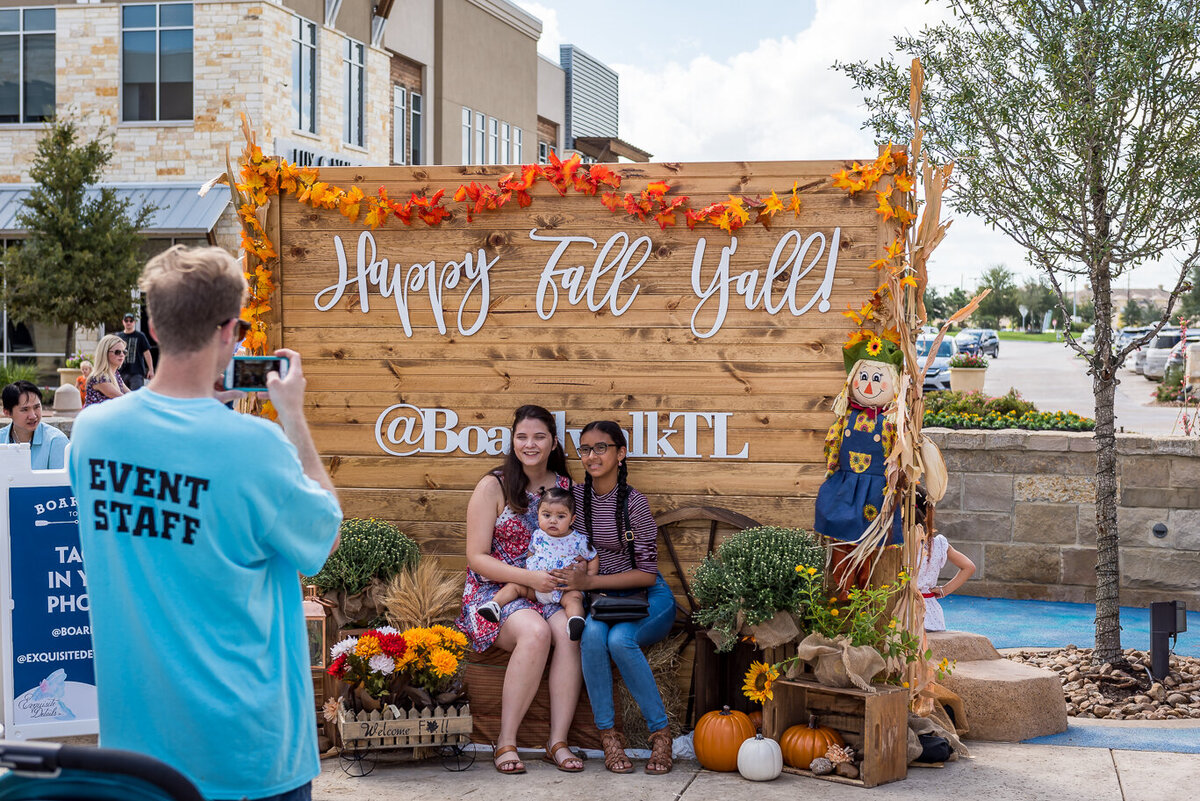 Family posing in front of a fall themed backdrop for a Boardwalk TL corporate event