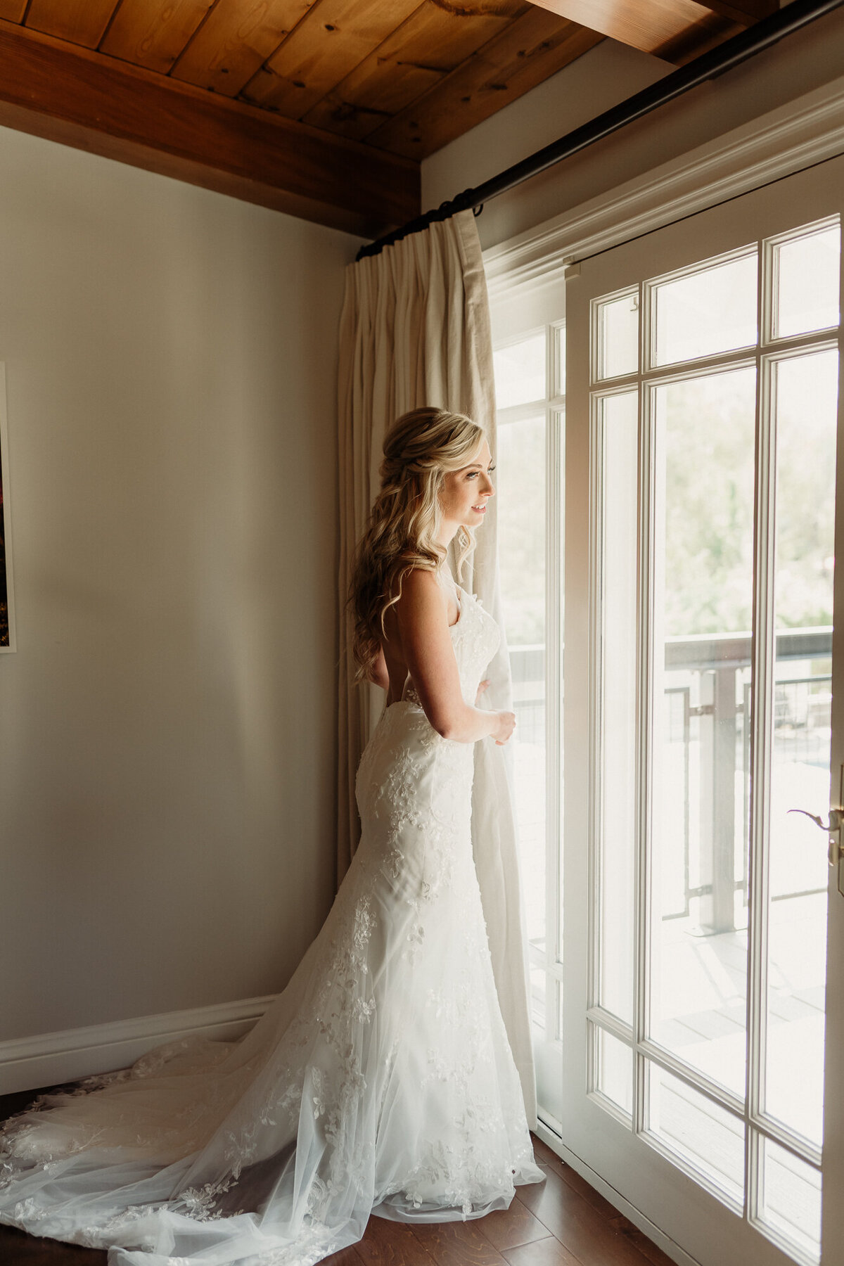 taken by los angeles wedding photographer - bride standing in a window looking out over her wedding venue