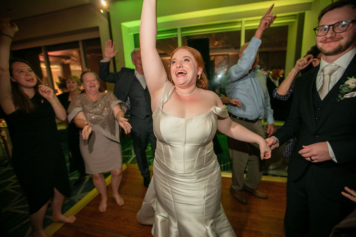 A woman in a white dress is dancing with her arms in the air.