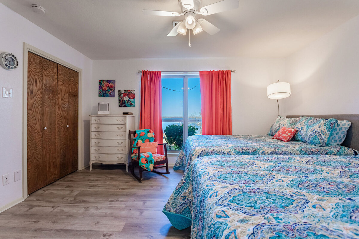 Bedroom that sleeps four and beautiful view of the lake in this 2-bedroom, 2-bathroom lakeside vacation rental home for 6 guests on Tradinghouse Lake with privacy access to a fishing dock and boat launch pad, ping pong table, gazebo, free wifi and free parking in Waco, TX.