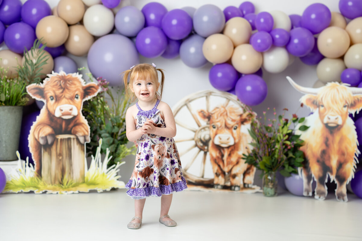 Girl enjoying a whimsical purple highland cow-themed birthday session, full of color and personality, photographed in Canton, GA by Victoria Lee Photography.
