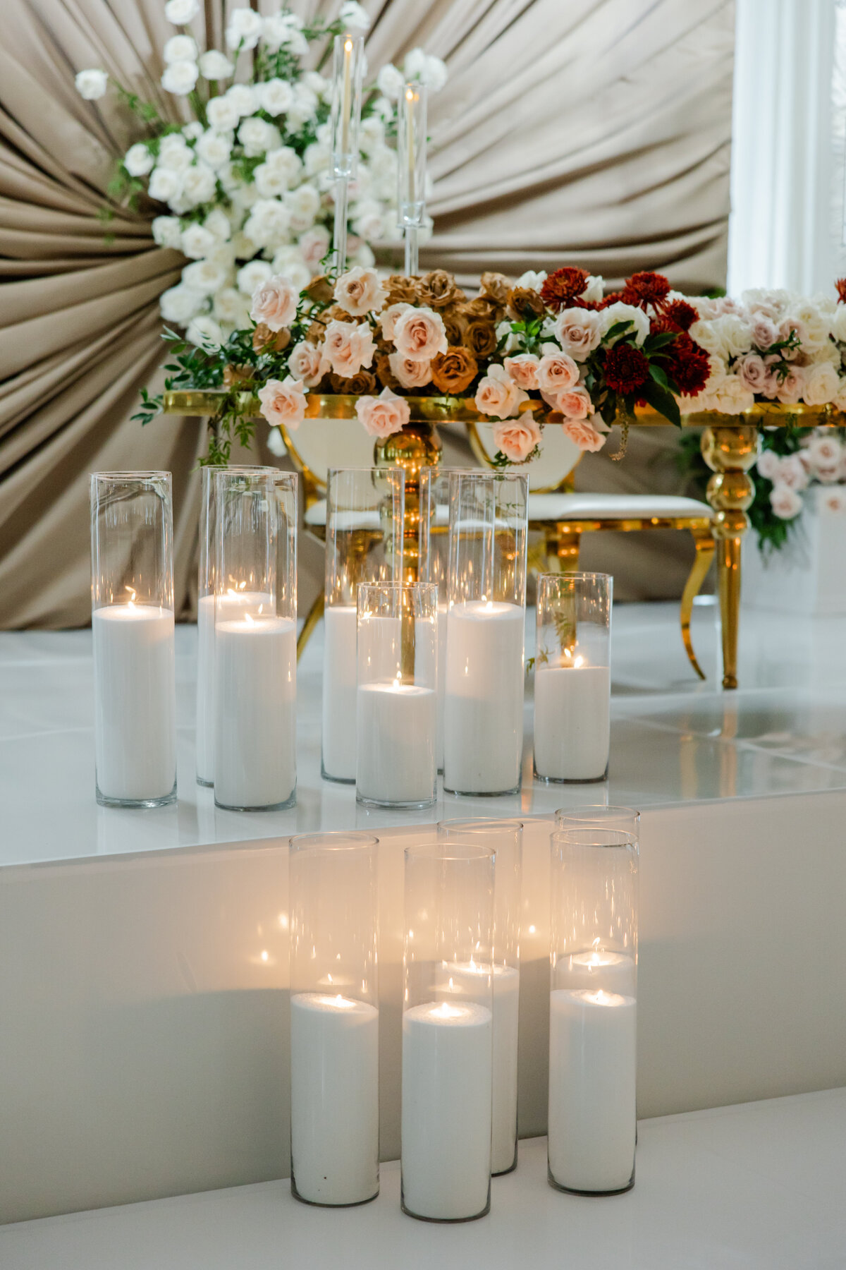 Softly glowing candles in glass containers nestled in sand, creating a warm and intimate ambiance.