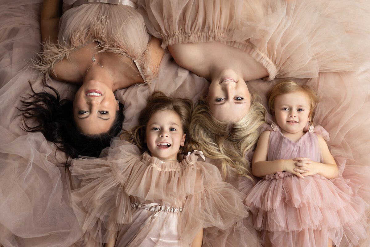 A mother and her daughters in matching pink dresses captured in a luxurious family photoshoot by a Dallas family photographer.