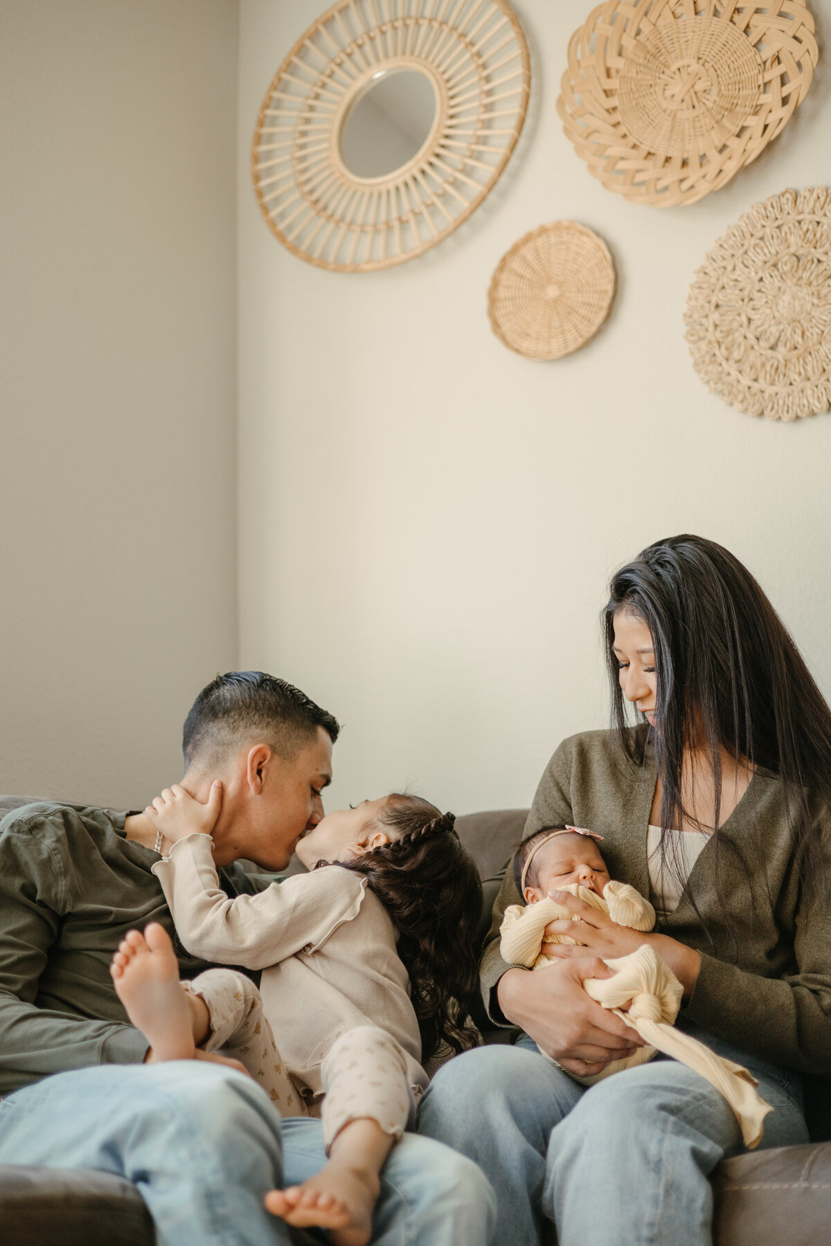 New family of four loving on each other while mom holds newborn baby during in home newborn session in Firestone Colorado