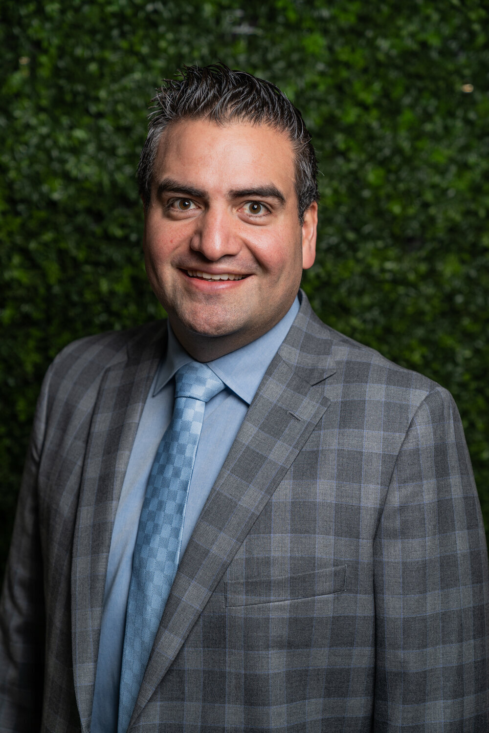 Young man posing in front of greenery wall for headshot for Houston freelance photographer