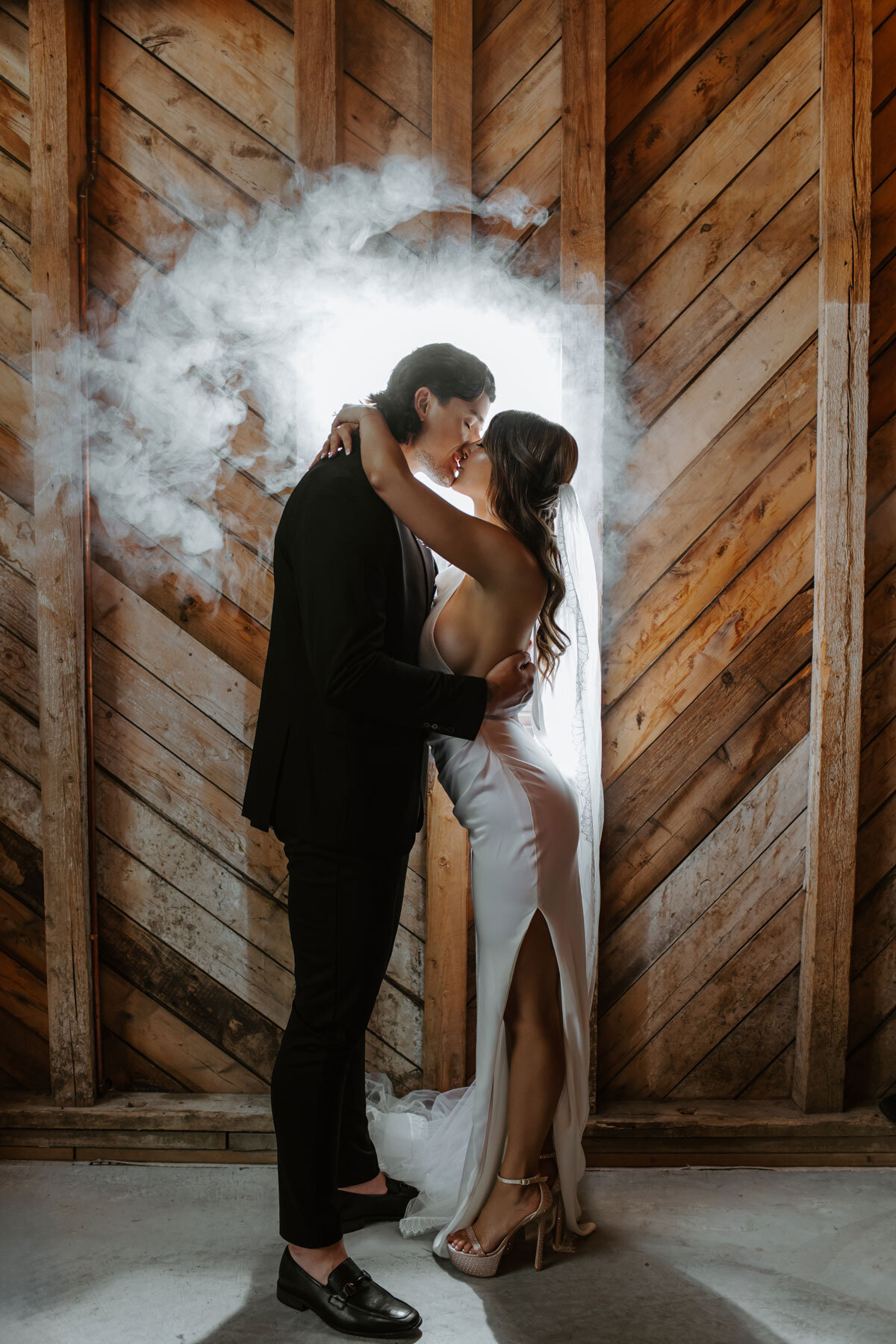 Bride and groom kissing with fog in the background.