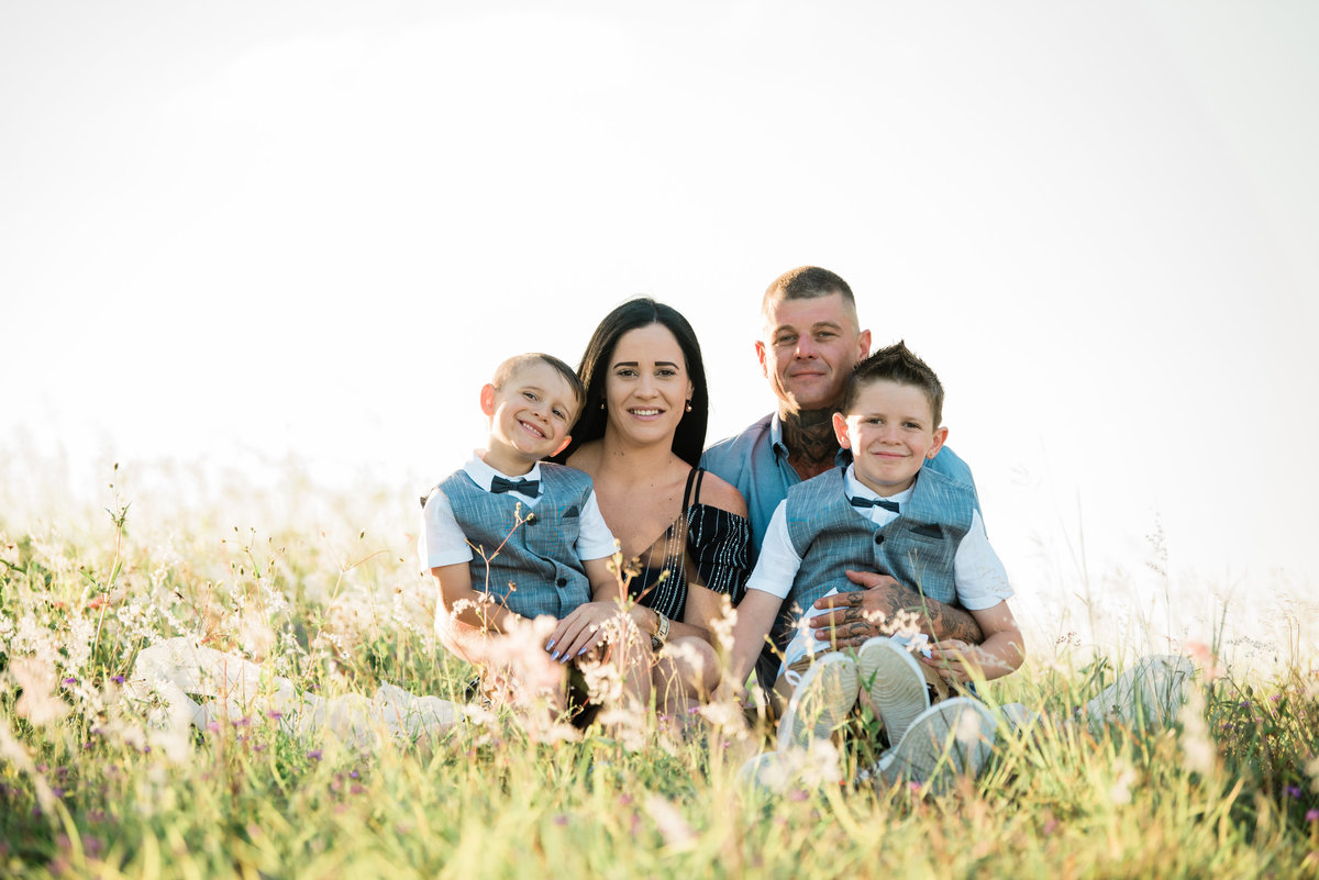 family-sitting-in-long-grassy-field-at-sunset-lead-images