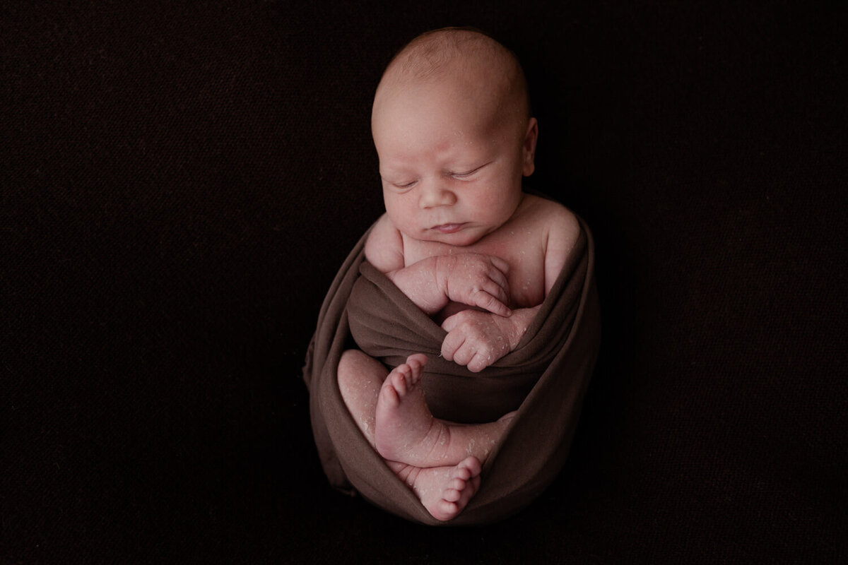 Een newborn shoot aan huis, waarbij effen achtergronden in zachte tinten zorgen voor een rustige sfeer en maken de foto’s tijdloos en puur.