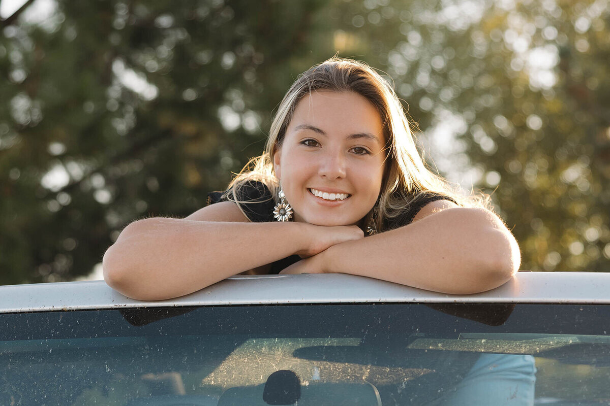 Senior girl smiling while sitting on her Jeep