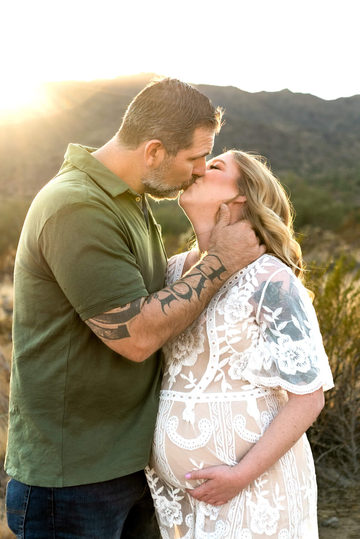husband softly kissing his glowing expecting wife at sunset for maternity photos
