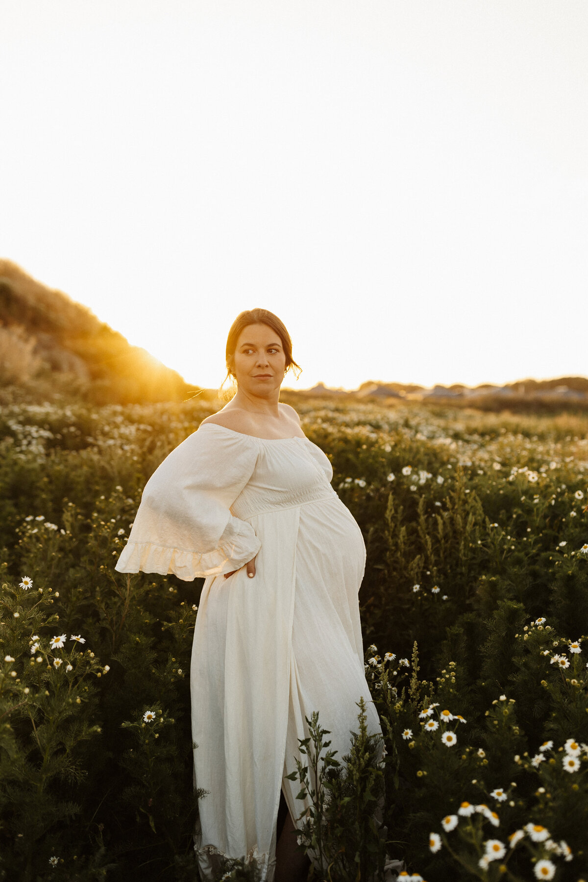 A beautiful mother to be wears a gorgeous dress from lucy jane photographys client wardrobe during a maternity photoshoot in christchurch