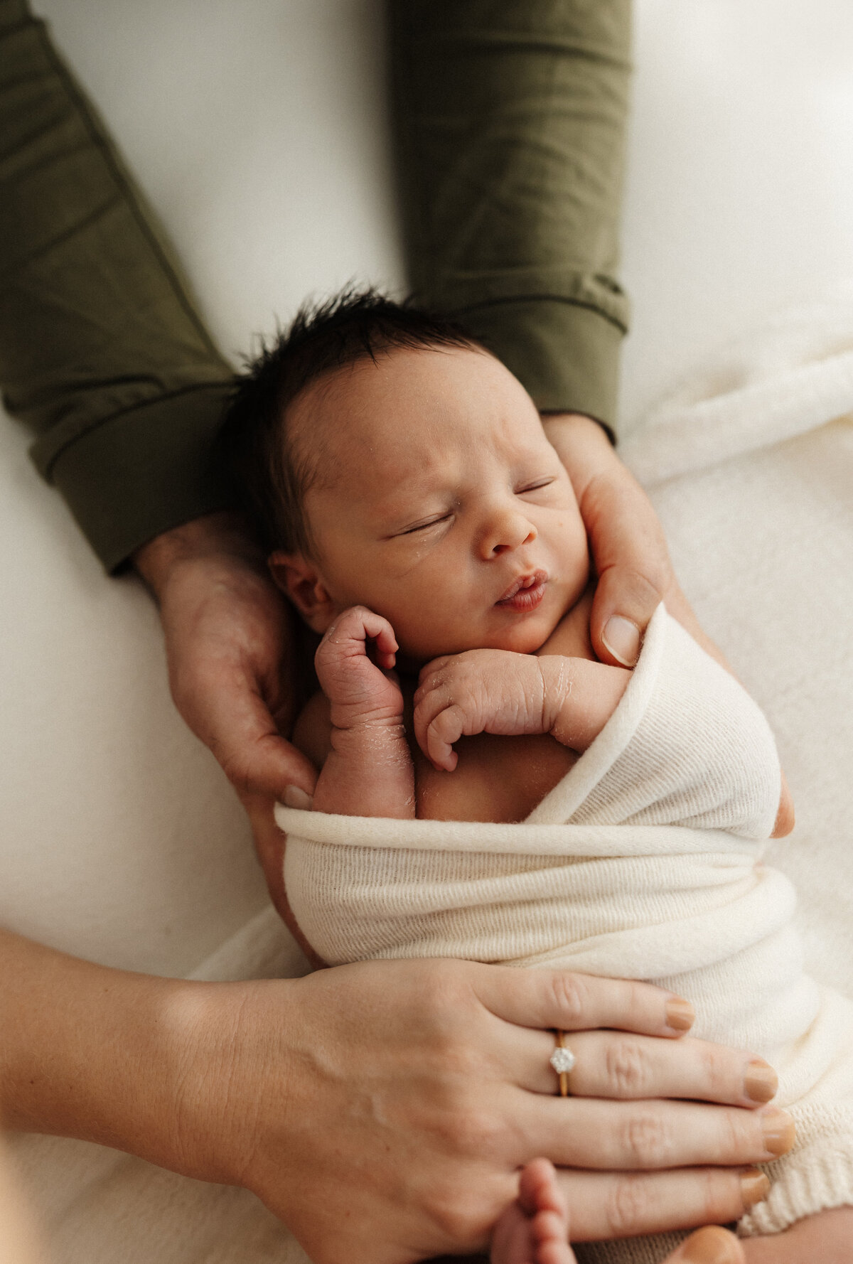 A father holding his newborn during a studio newborn photoshoot with christchurch photographer lucy jane