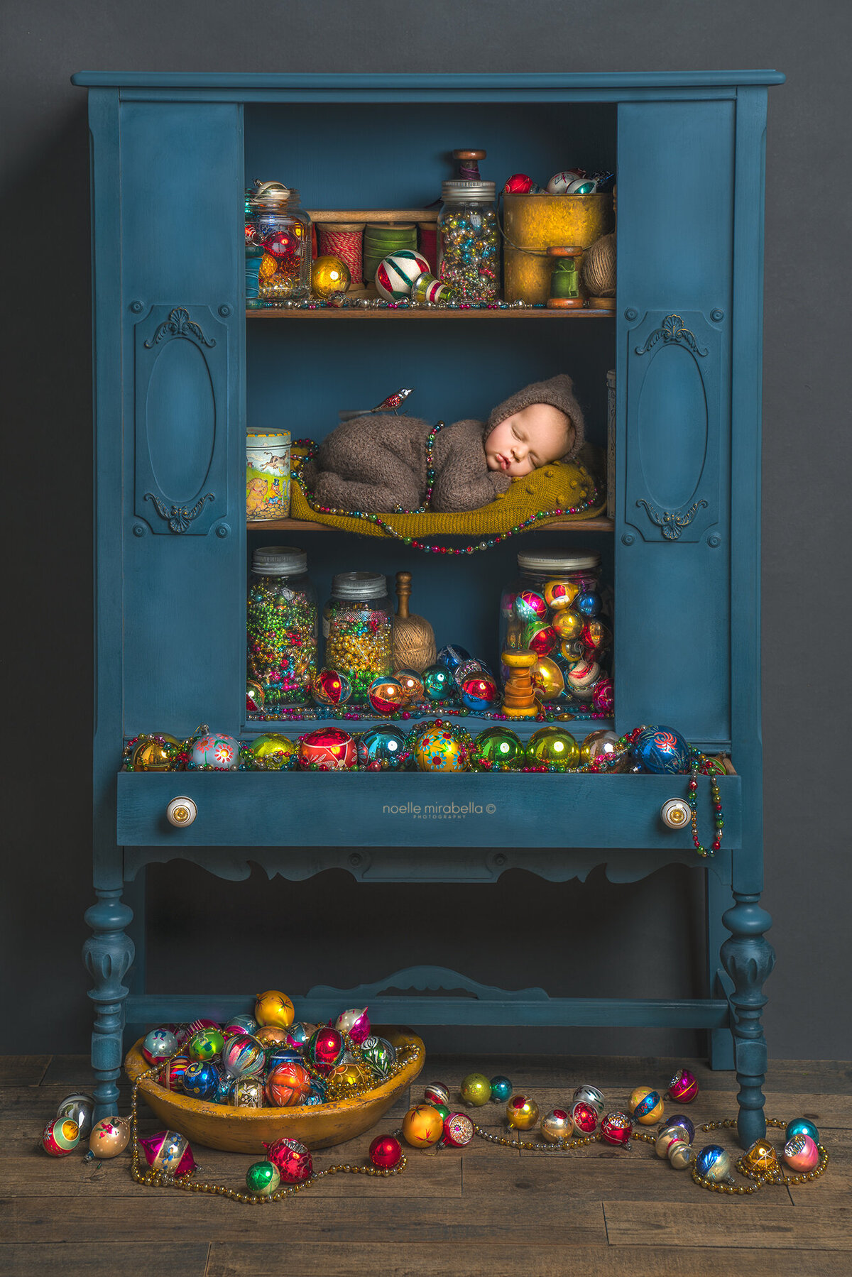 Baby sleeping in cupboard full of vintage antique Christmas ornaments