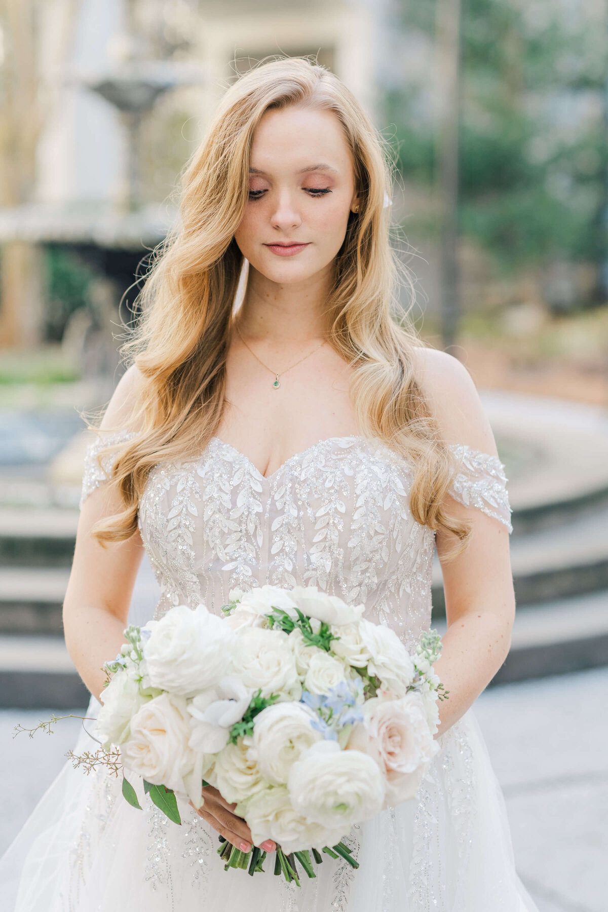 Bride looking down at wedding bouquet standing in a courtyard