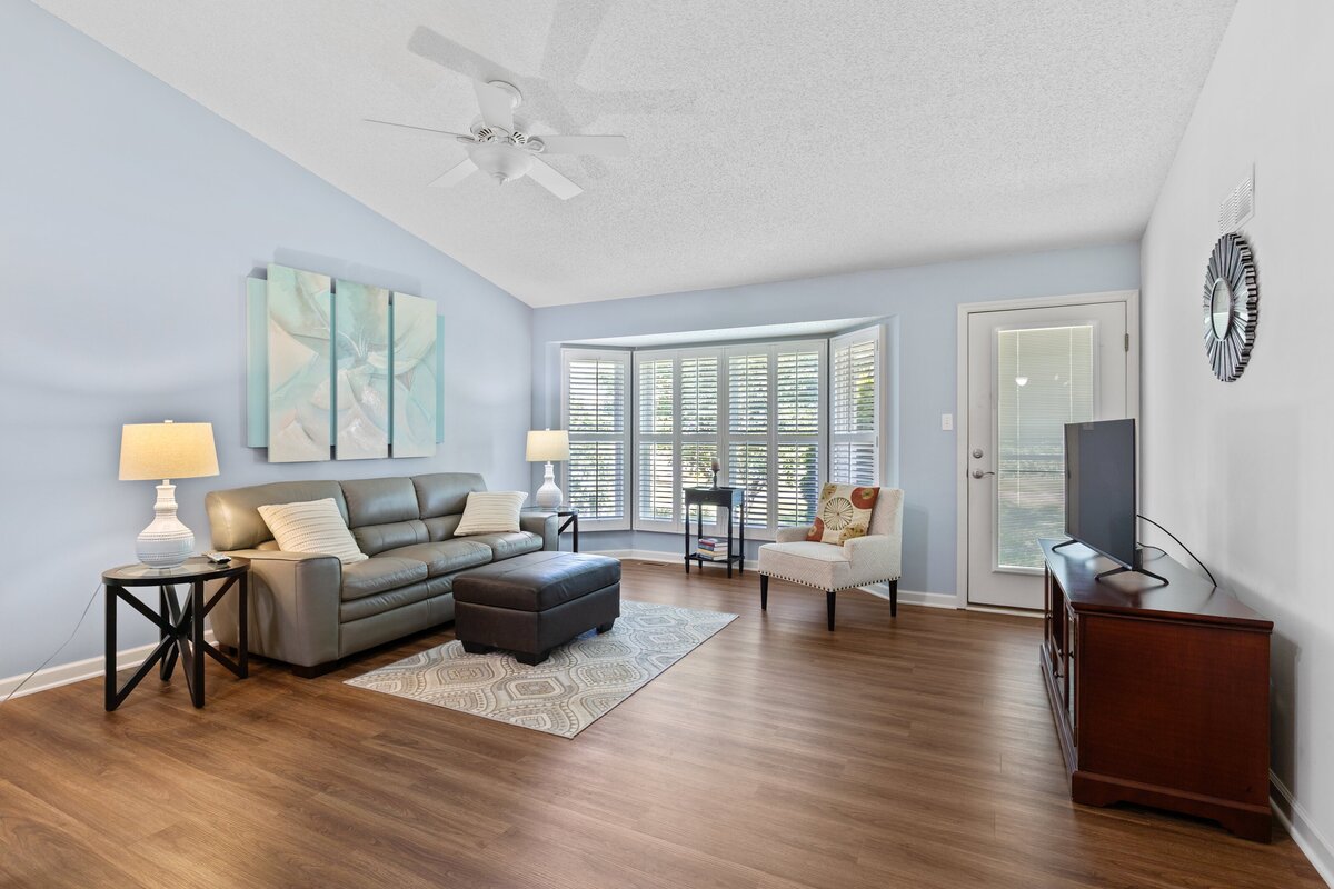 Real estate photo of the interior of a home. Showing a light blue living room with high ceilings and lots of windows. 
