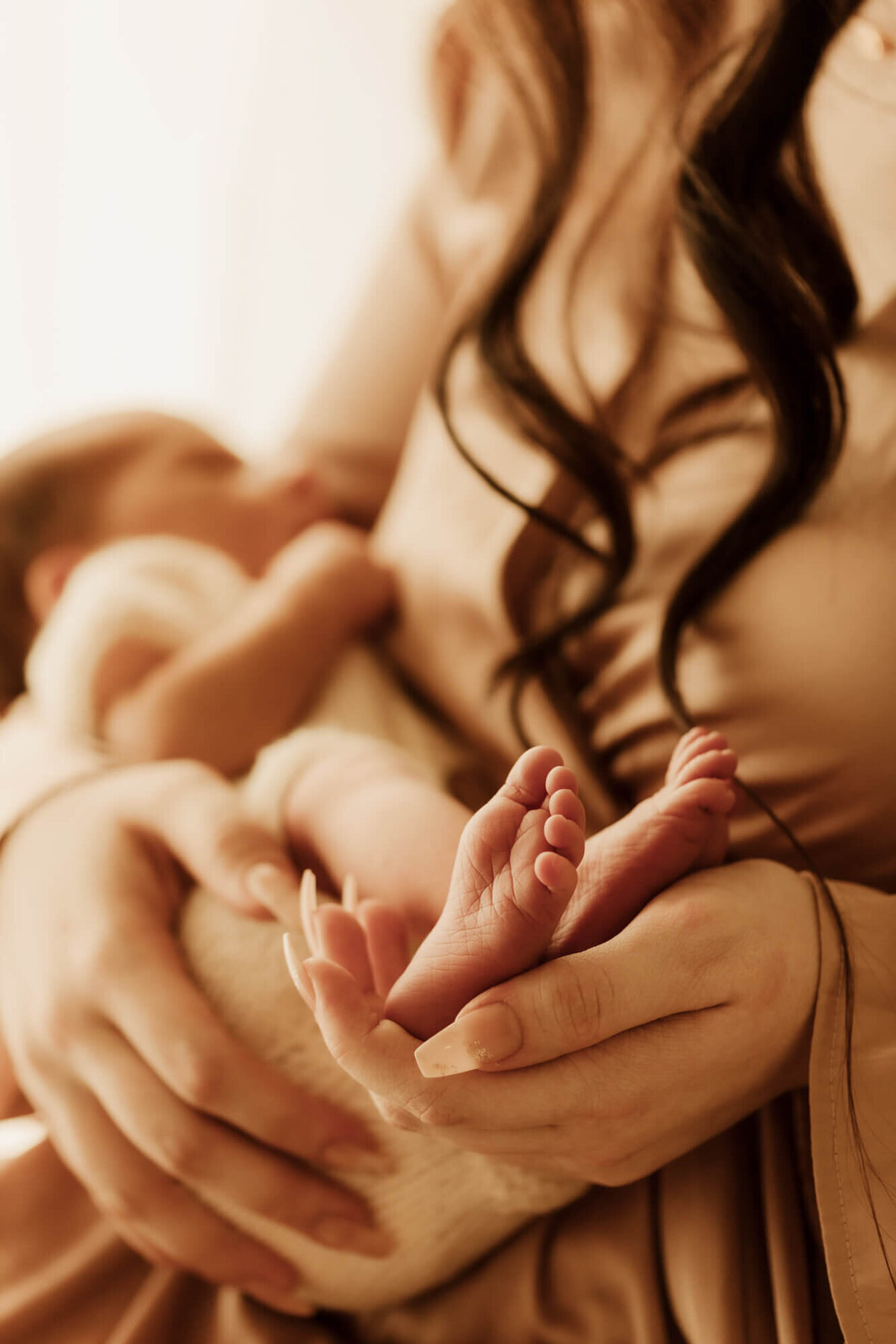 Mother holds baby boy's feet.