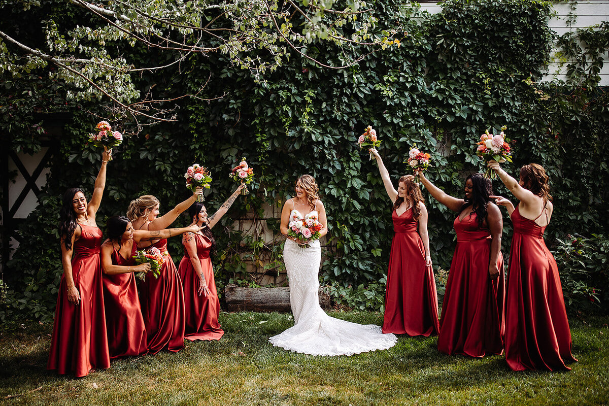 Bride with her bridesmaids in rust dresses and rust and peach bouquets.