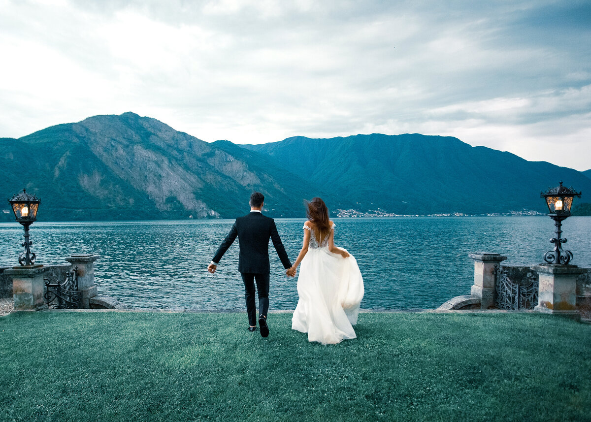 A wedding couple walking towards a lake in Lake Como, Italy on an overcast day/