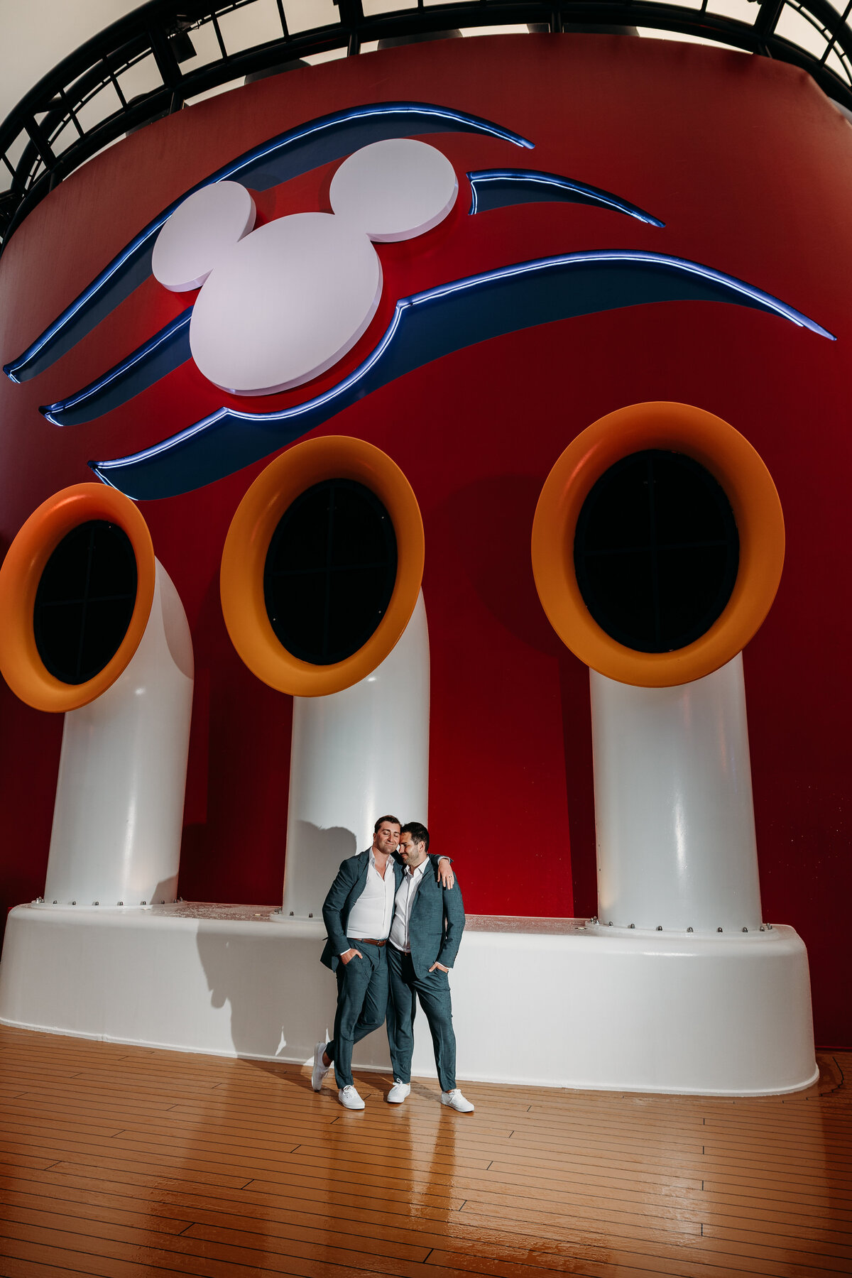 Grooms hugging and smiling at the stacks on Disney Fantasy Cruise Ship
