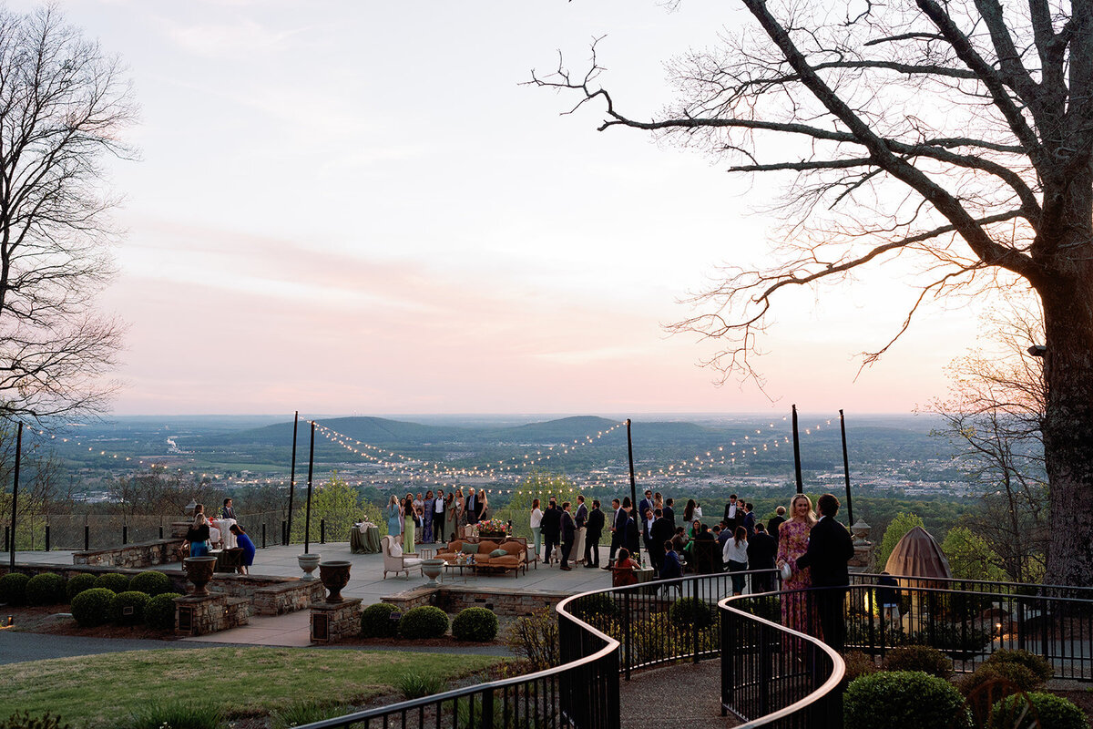Guests mingling outdoors under string lights with panoramic mountain views during sunset at Burritt on the Mountain.