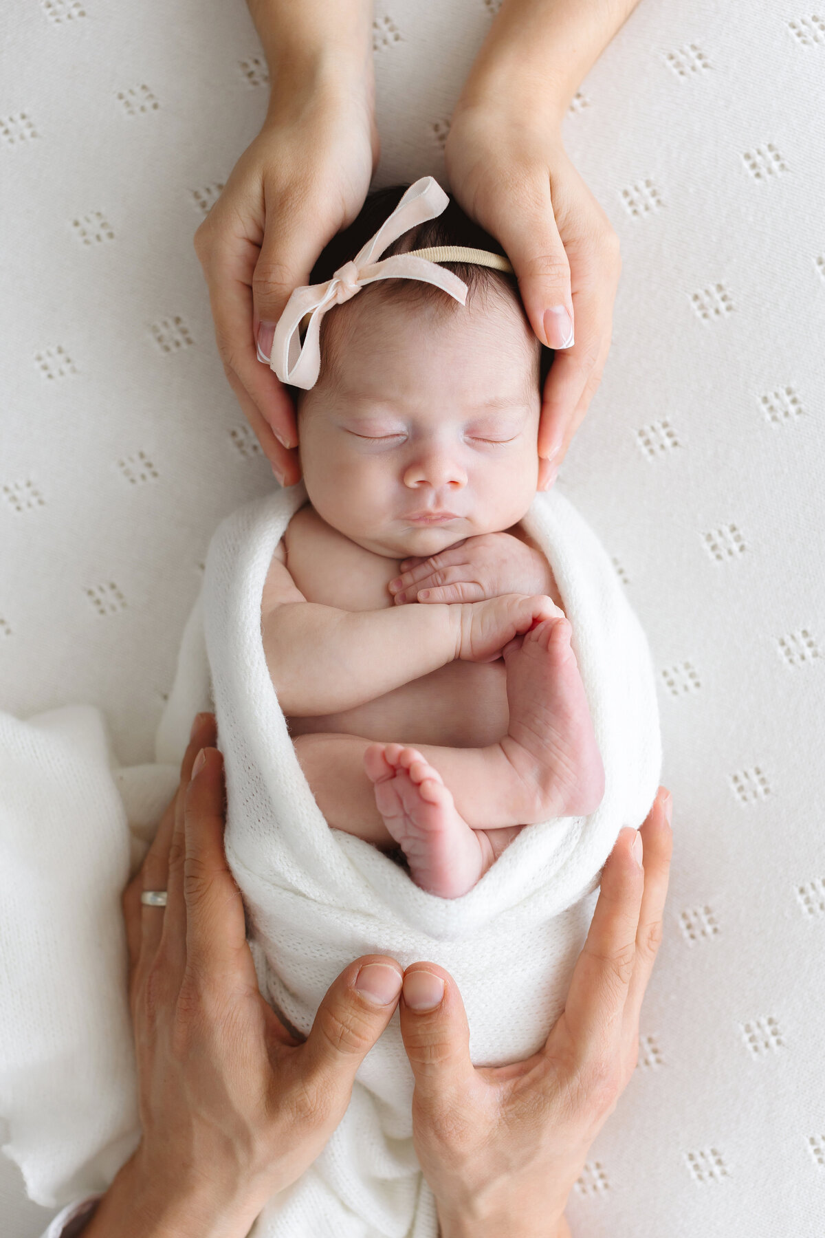 newborn wrapped held by parents hands