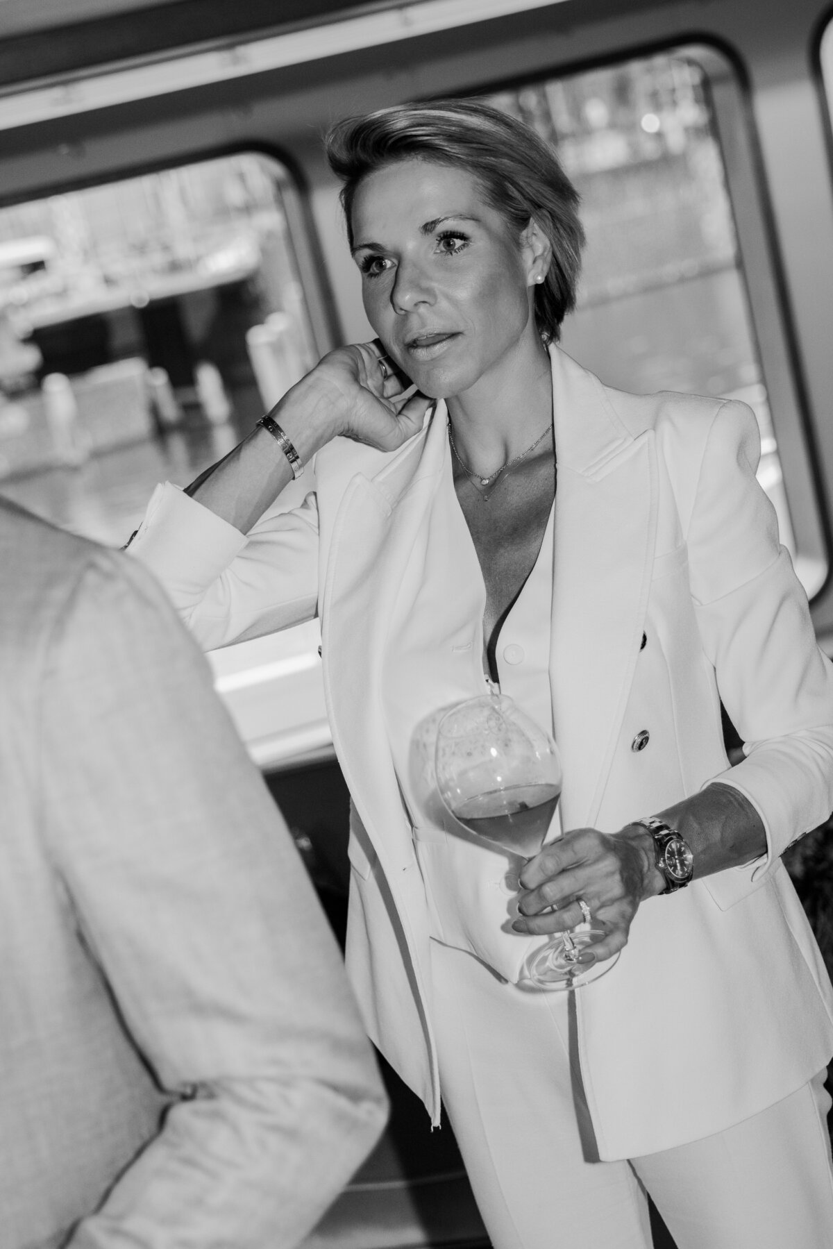 An elegant woman holding a glass of wine aboard the Samadhi yacht, her stylish attire perfectly complementing the sophisticated ambiance of the event. A prime example of luxury lifestyle photography.