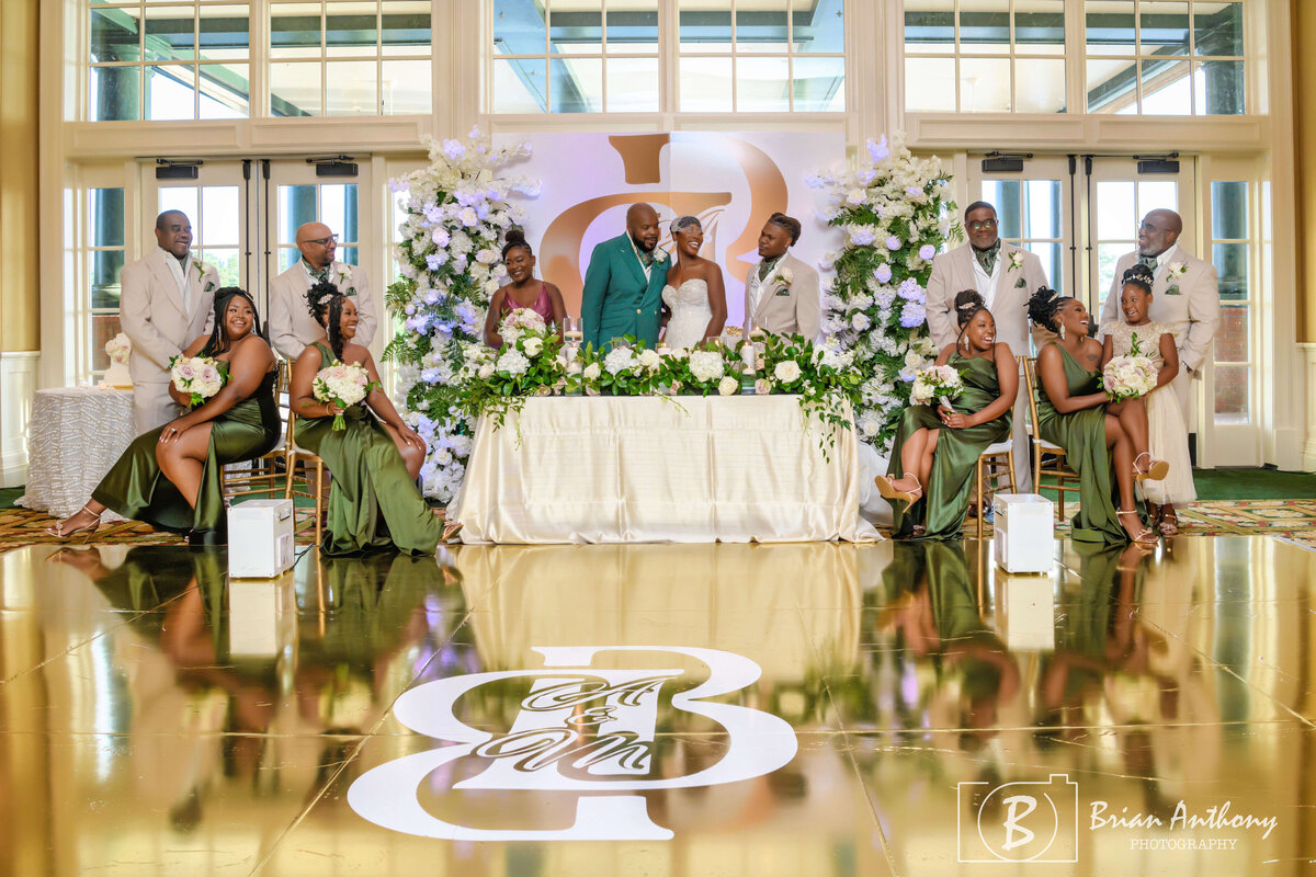 Newlyweds seated at their stunning reception table, surrounded by lush florals and decor.