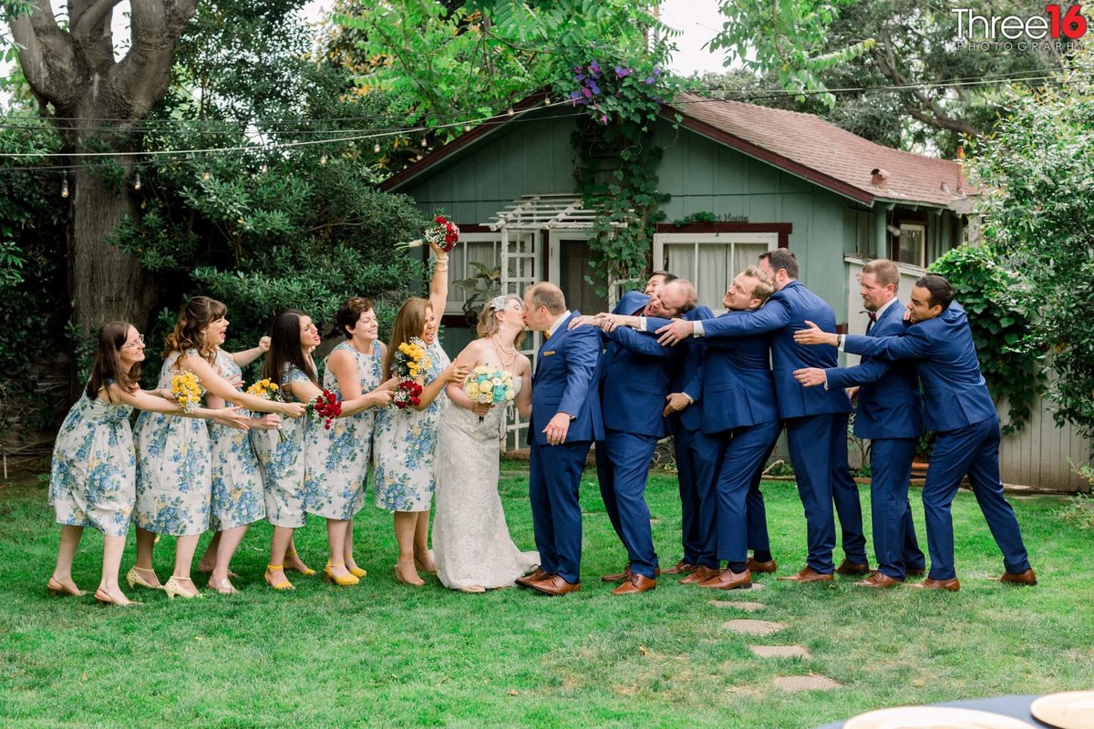 Bridal Party act silly as the Bride and Groom kiss
