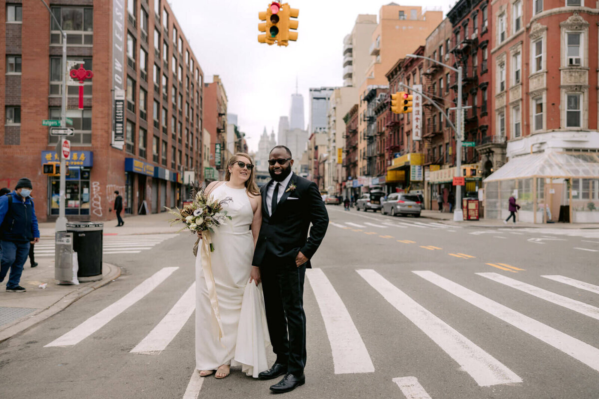 The bride and the groom are standing in the middle of a pedestrian lane in New York City.