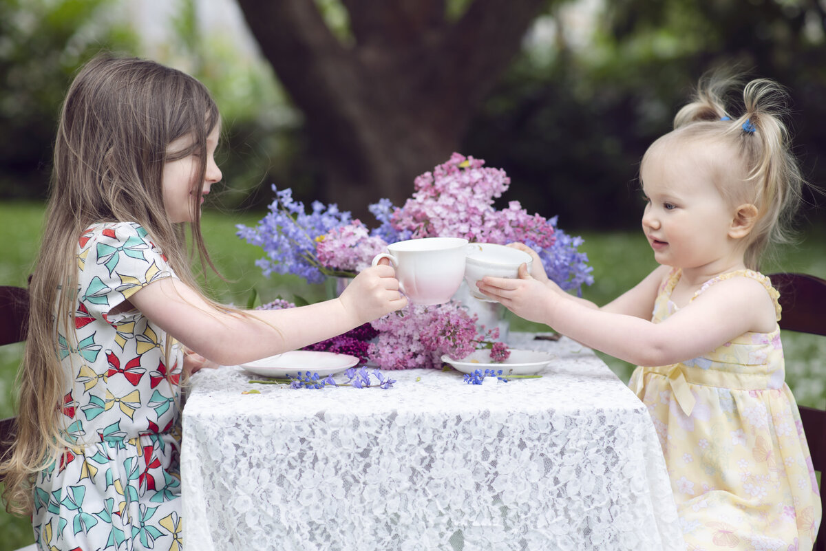 Two girls clinking teacups together
