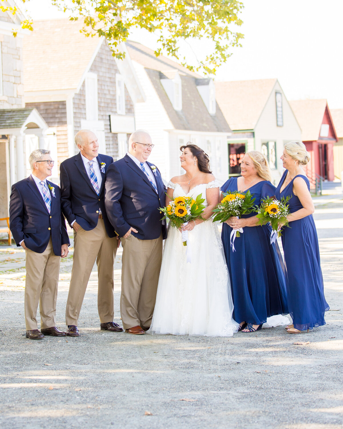 Bride and groom laugh with their groomsmen and bridesmaids at the Mystic Seaport.