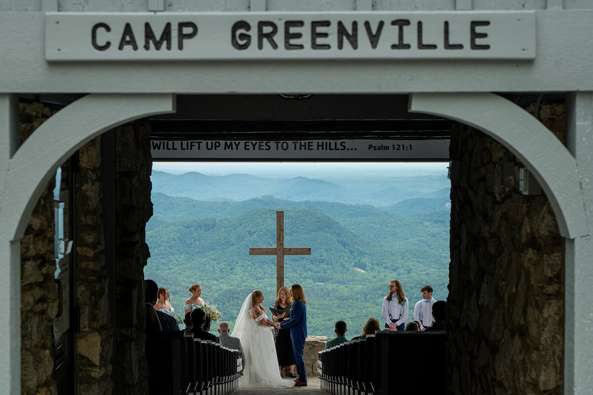 Wedding bride and groom getting married in front of a cross and a mountain view