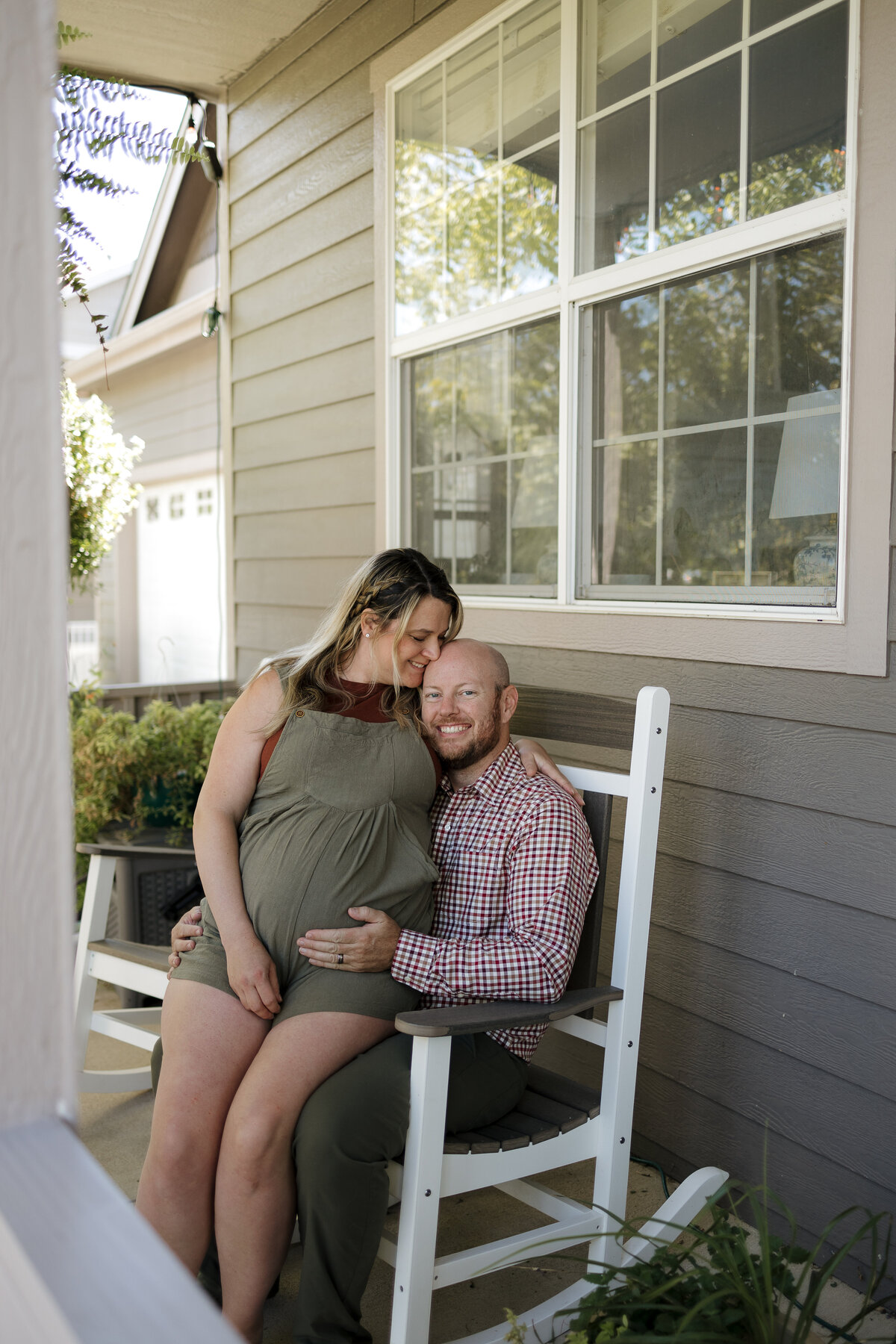 expectant-parents-sitting-on-rocking-chair-out-front-of-home-in-longmont-colorado